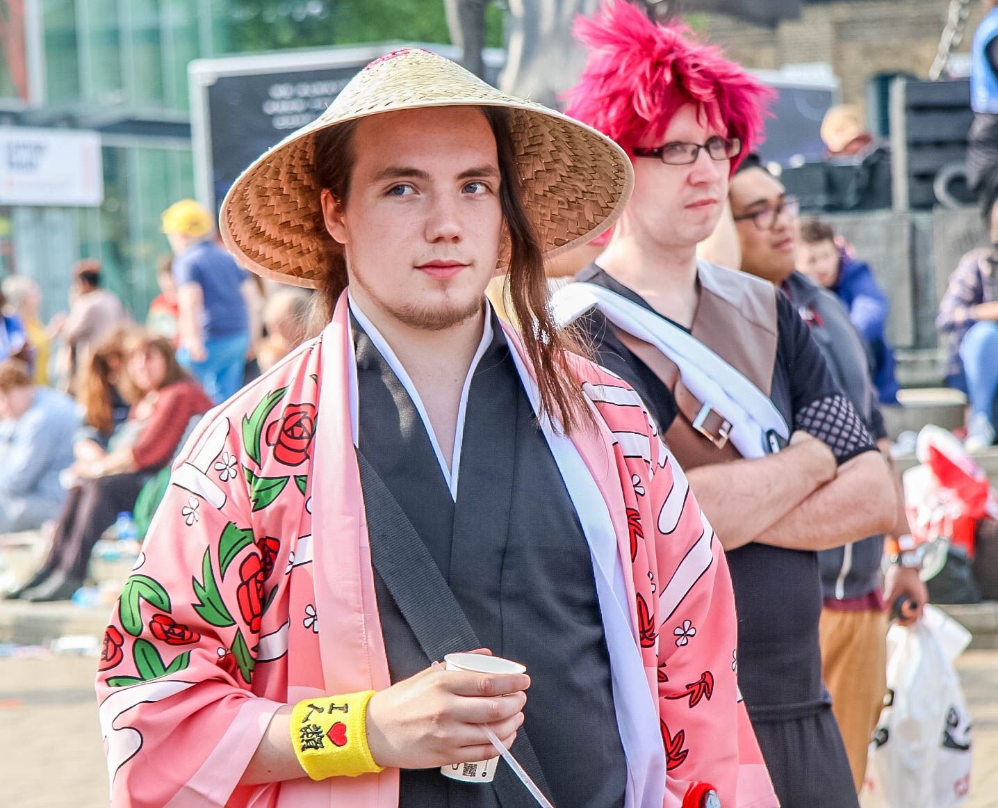 Bleach cosplayers at a comic convention, one in a straw hat and a pink flowered robe